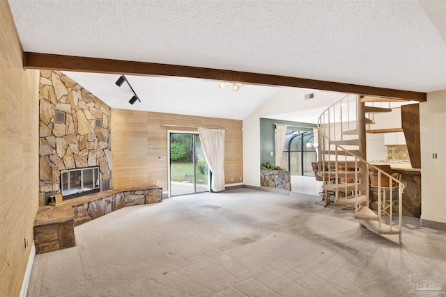 unfurnished living room with a stone fireplace, a textured ceiling, stairs, and carpet