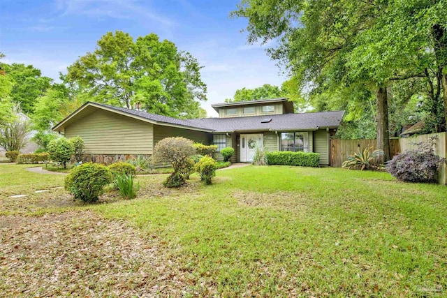 view of front of house featuring fence, roof with shingles, and a front yard