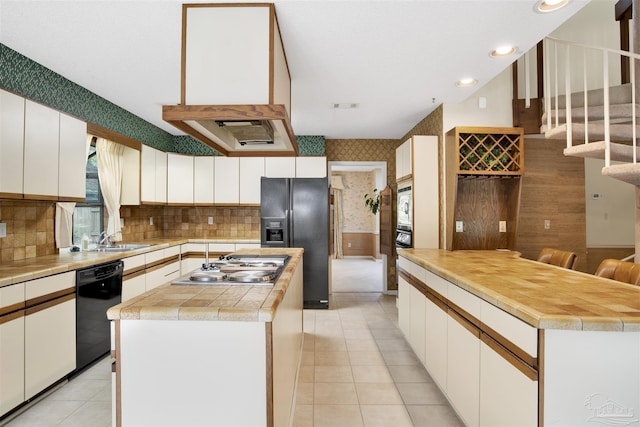 kitchen with a sink, decorative backsplash, black appliances, a kitchen island, and light tile patterned floors