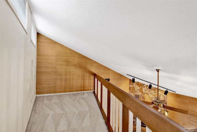 hallway with light carpet, vaulted ceiling, and baseboards