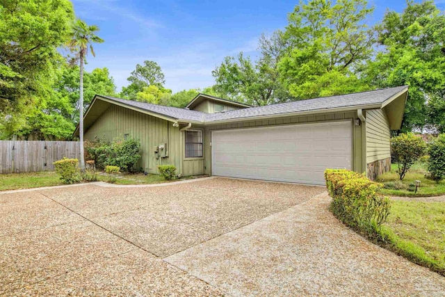 ranch-style home featuring fence, an attached garage, a shingled roof, and concrete driveway