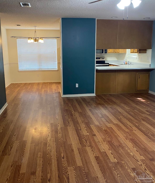 kitchen featuring decorative light fixtures, a textured ceiling, stainless steel appliances, and dark wood-type flooring