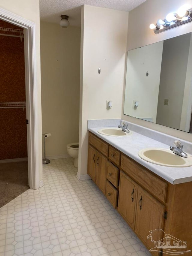 bathroom featuring vanity, toilet, and a textured ceiling