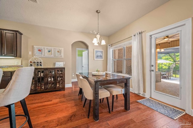 8847 Salt Grass Dr, Pensacola, FL 32526 - dining area featuring arched walkways, baseboards, a notable chandelier, and wood finished floors