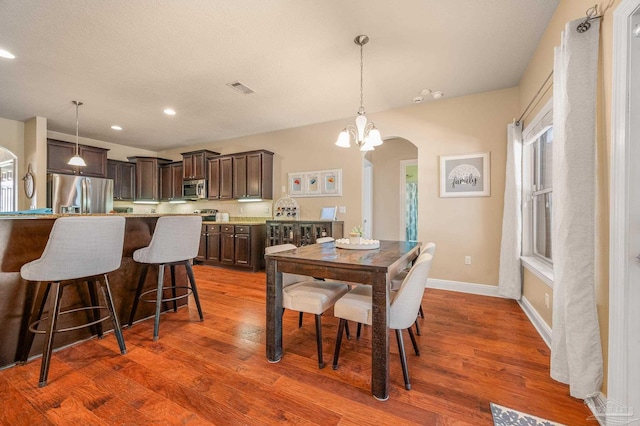 8847 Salt Grass Dr, Pensacola, FL 32526 - dining room featuring visible vents, arched walkways, wood finished floors, and a notable chandelier