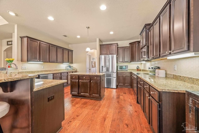 8847 Salt Grass Dr, Pensacola, FL 32526 - kitchen with light stone counters, light wood-type flooring, dark brown cabinetry, and stainless steel appliances