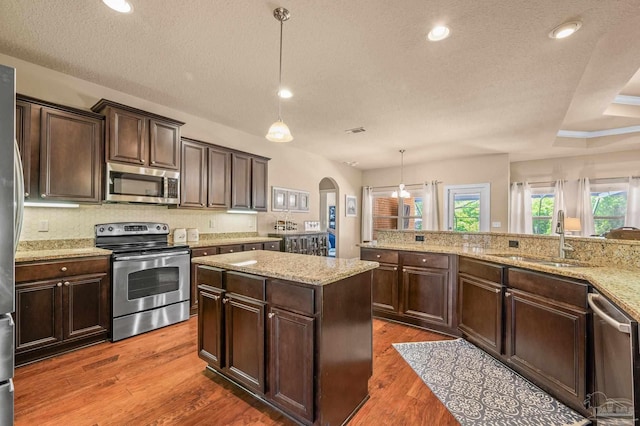8847 Salt Grass Dr, Pensacola, FL 32526 - kitchen featuring dark brown cabinets, a textured ceiling, arched walkways, a sink, and appliances with stainless steel finishes