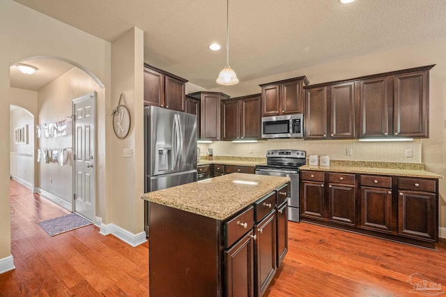 8847 Salt Grass Dr, Pensacola, FL 32526 - kitchen featuring arched walkways, stainless steel appliances, a textured ceiling, and dark brown cabinets