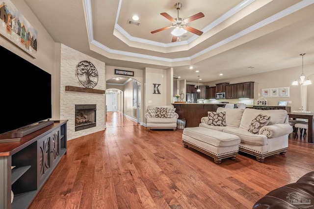 8847 Salt Grass Dr, Pensacola, FL 32526 - living room featuring crown molding, arched walkways, ceiling fan with notable chandelier, a tray ceiling, and visible vents
