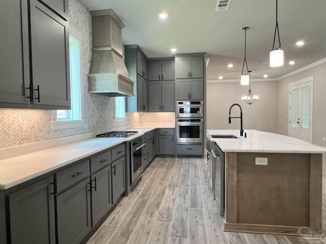 2440 Meeting St, Cantonment, FL 32533 - kitchen with sink, stainless steel appliances, custom range hood, a center island with sink, and decorative light fixtures