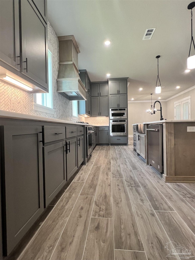 2440 Meeting St, Cantonment, FL 32533 - kitchen featuring appliances with stainless steel finishes, gray cabinetry, hanging light fixtures, custom exhaust hood, and light hardwood / wood-style flooring
