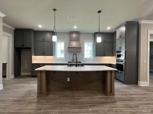 2440 Meeting St, Cantonment, FL 32533 - kitchen featuring tasteful backsplash, custom exhaust hood, stainless steel double oven, and a center island with sink