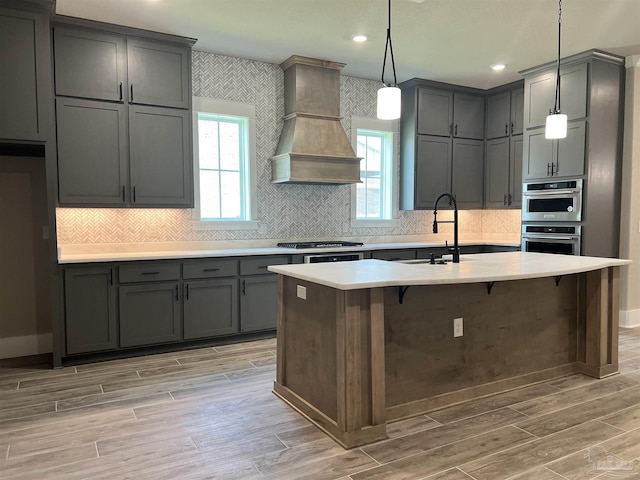2440 Meeting St, Cantonment, FL 32533 - kitchen with premium range hood, gray cabinetry, hanging light fixtures, light wood-type flooring, and stainless steel appliances