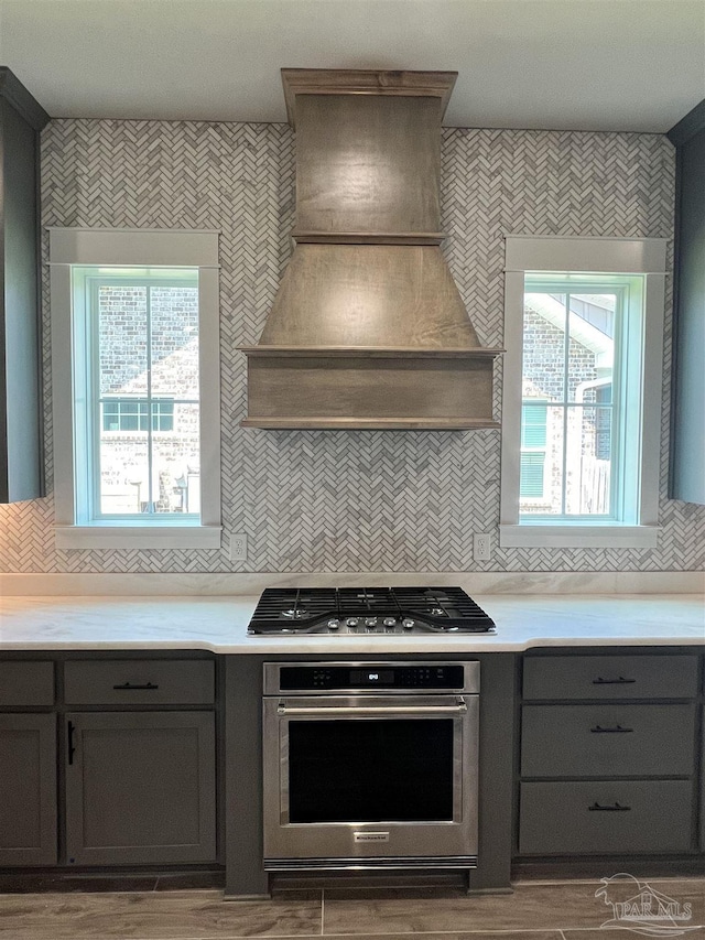 2440 Meeting St, Cantonment, FL 32533 - kitchen featuring gray cabinetry, decorative backsplash, stainless steel appliances, and custom range hood