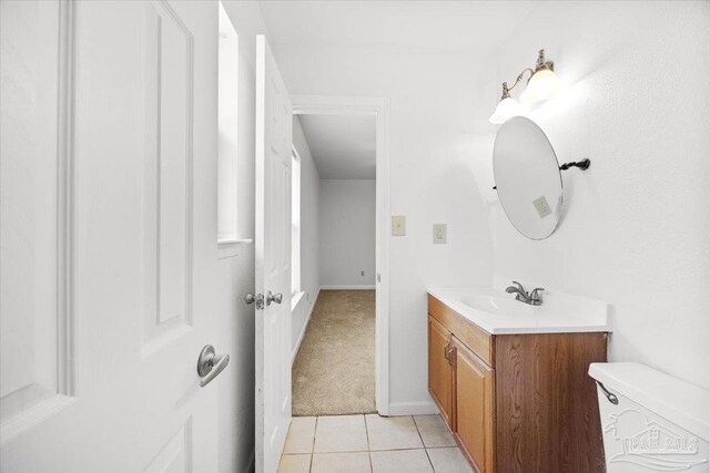half bathroom with vanity, tile patterned flooring, toilet, and baseboards