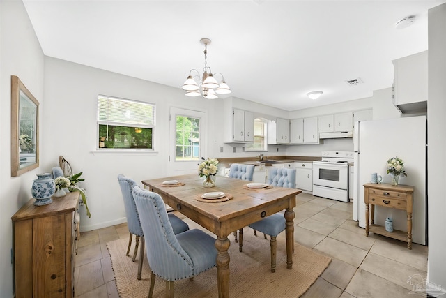 dining space with a chandelier, light tile patterned floors, and baseboards