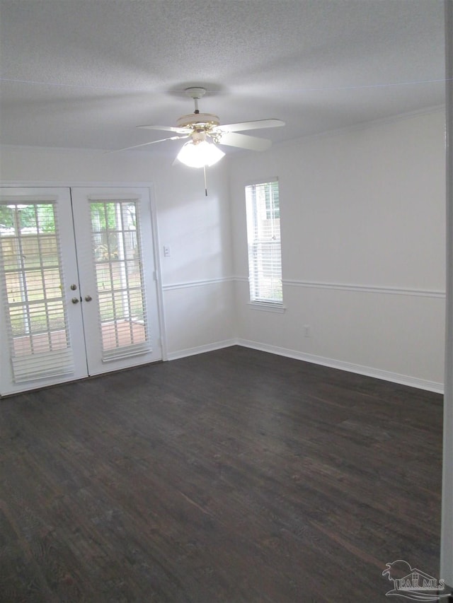 spare room with dark wood-type flooring, healthy amount of natural light, a ceiling fan, french doors, and a textured ceiling