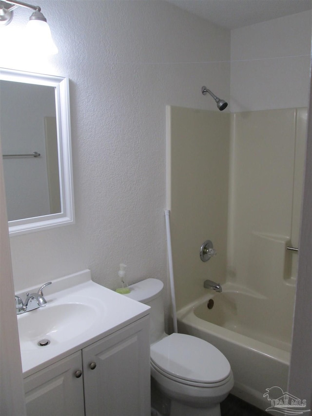 full bath featuring a textured wall, vanity, toilet, and shower / tub combination