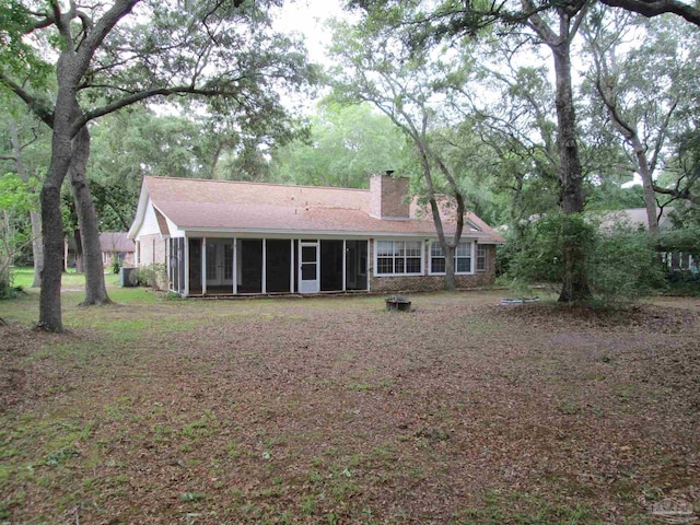 back of property with a sunroom and a chimney