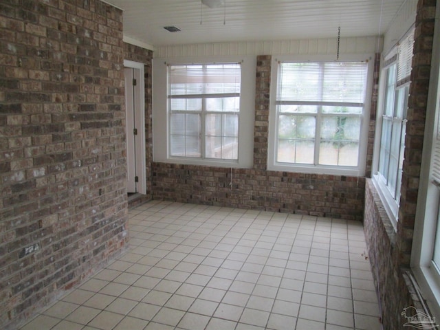 unfurnished sunroom with brick wall and tile patterned floors