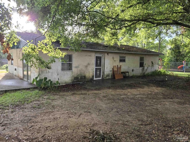 35 N Cypress St, Mcdavid, FL 32568 - rear view of house featuring concrete block siding, a patio, and a shingled roof