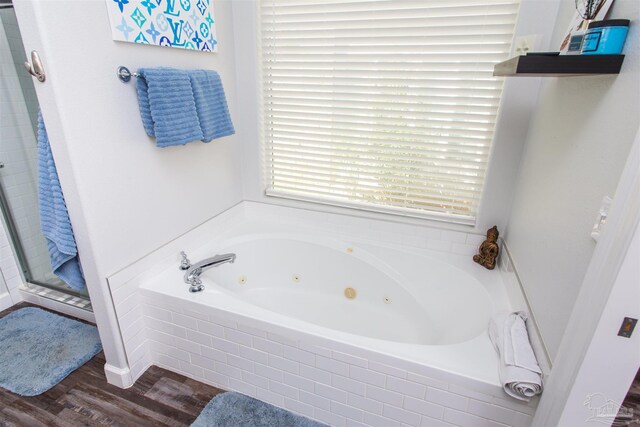 bathroom with wood-type flooring and tiled bath