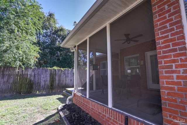 exterior space featuring a lawn, a sunroom, and ceiling fan