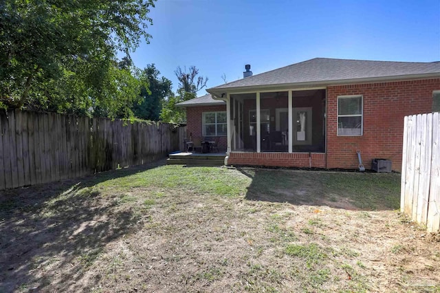 rear view of house with a wooden deck, a yard, and a sunroom