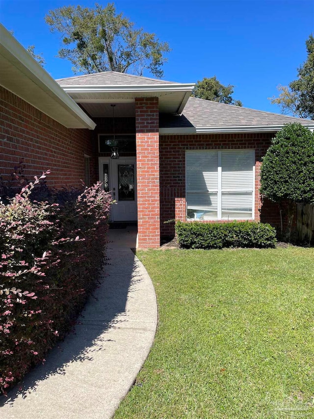 view of exterior entry featuring a lawn