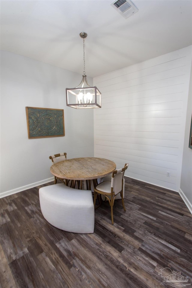 dining space with dark hardwood / wood-style flooring and an inviting chandelier