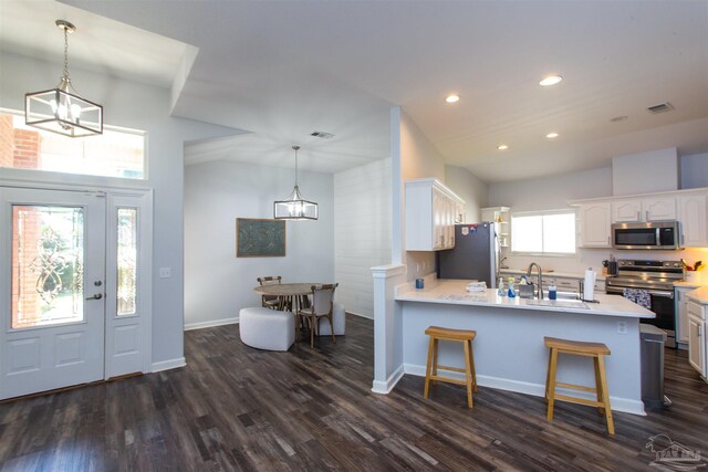 kitchen featuring dark hardwood / wood-style floors, stainless steel appliances, sink, decorative light fixtures, and white cabinetry