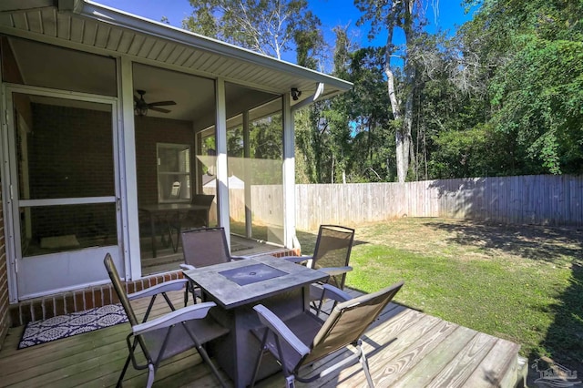 deck featuring a sunroom, a lawn, and ceiling fan