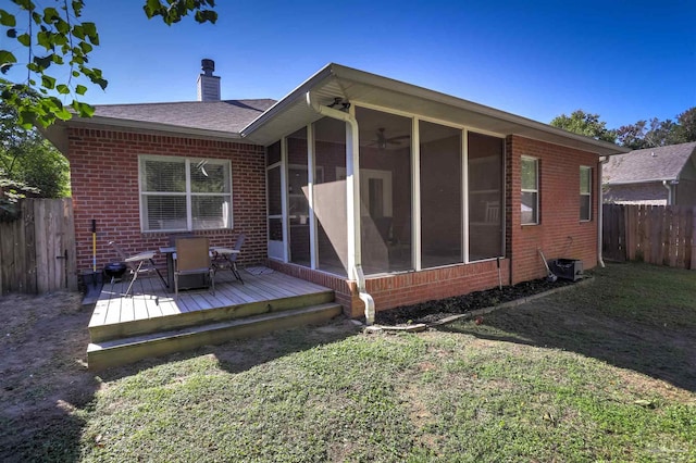 rear view of property with a deck, a lawn, and a sunroom