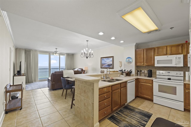kitchen with light tile patterned floors, a sink, open floor plan, white appliances, and ornamental molding