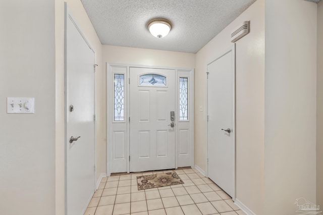 foyer with baseboards, a textured ceiling, and light tile patterned flooring