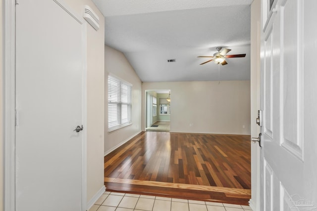 foyer entrance with light tile patterned floors, ceiling fan, a textured ceiling, lofted ceiling, and visible vents