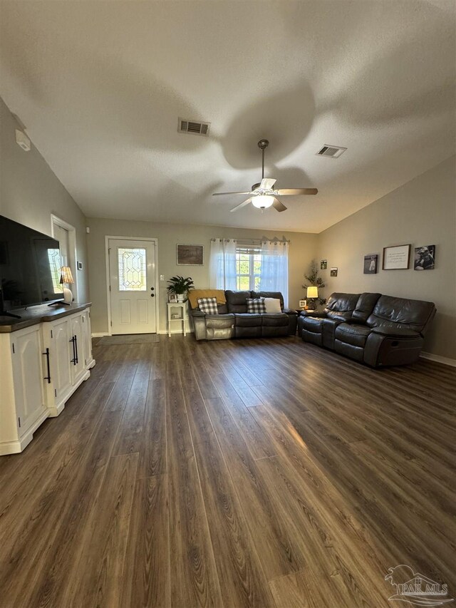 living room with visible vents, vaulted ceiling, and dark wood finished floors