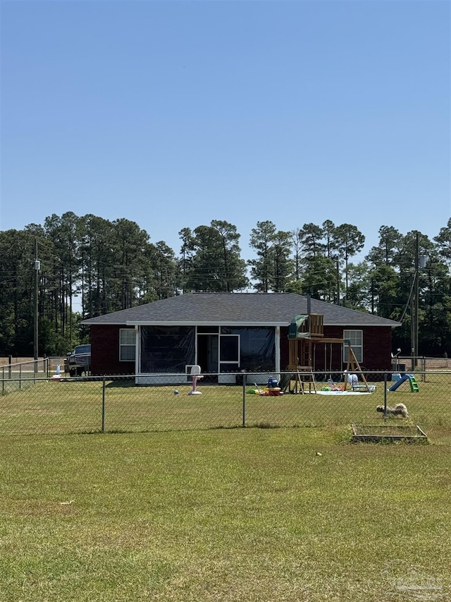 back of house featuring fence, a lawn, and a playground