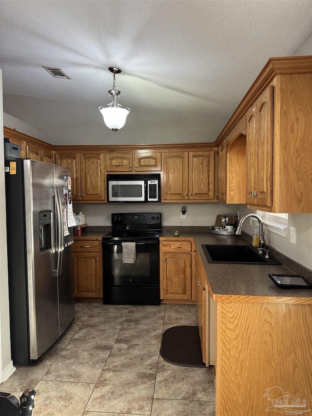 kitchen with brown cabinetry, appliances with stainless steel finishes, dark countertops, a sink, and visible vents