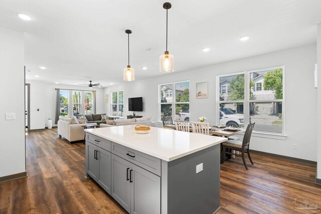 kitchen featuring hanging light fixtures, a kitchen island, gray cabinets, and dark wood-type flooring