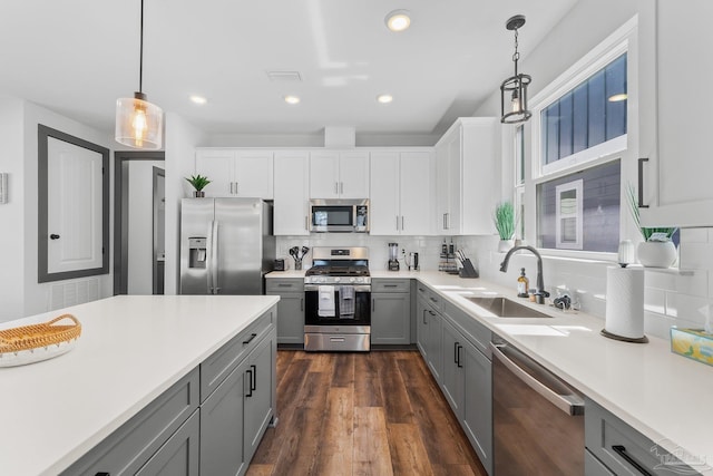 kitchen featuring sink, gray cabinetry, white cabinetry, hanging light fixtures, and stainless steel appliances