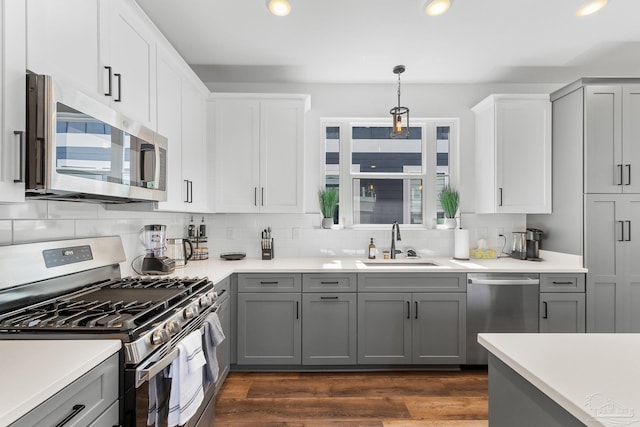 kitchen featuring gray cabinetry, sink, hanging light fixtures, and appliances with stainless steel finishes