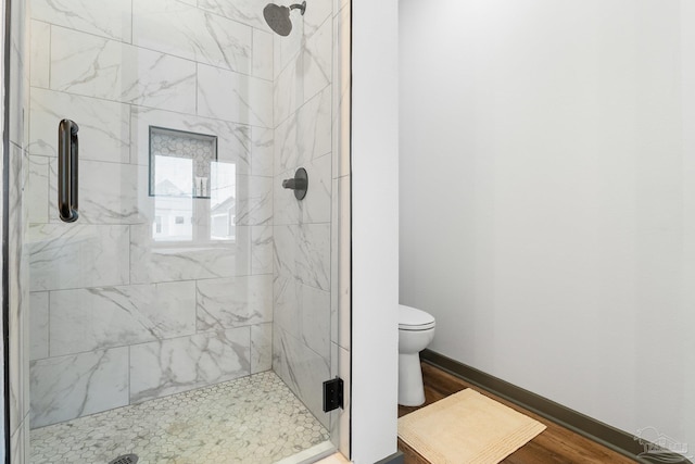 bathroom with wood-type flooring, toilet, and a shower with shower door