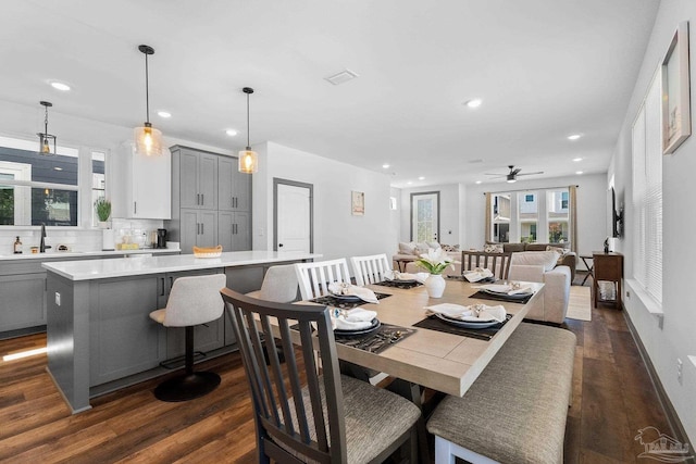 dining room with ceiling fan, sink, and dark hardwood / wood-style flooring