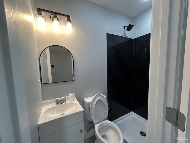 bathroom with vanity, toilet, and tiled shower