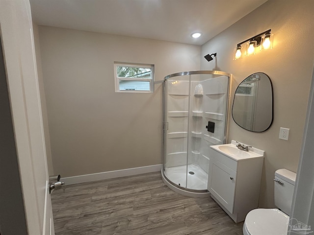 bathroom featuring vanity, hardwood / wood-style floors, a shower with shower door, and toilet