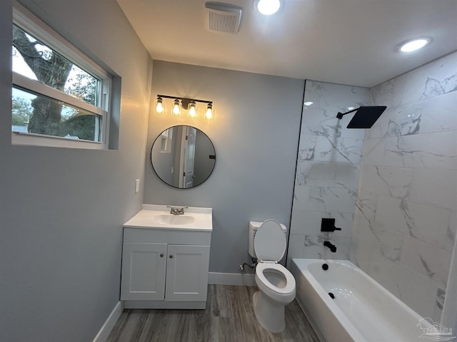 full bathroom with hardwood / wood-style flooring, tiled shower / bath, vanity, and toilet