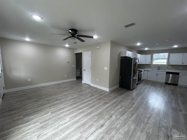 kitchen with sink, ceiling fan, appliances with stainless steel finishes, white cabinets, and light wood-type flooring