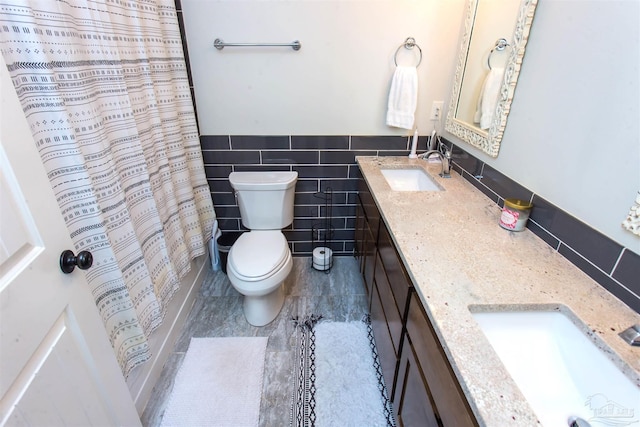 bathroom featuring a sink, toilet, tile walls, and double vanity