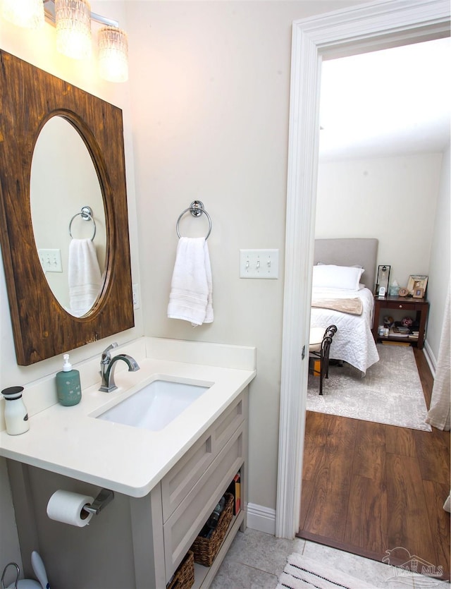 bathroom with vanity, wood finished floors, baseboards, and connected bathroom